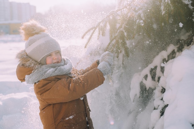 Il bambino scuote un ramo con la neve natura invernale un articolo sull'inverno