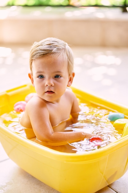 子供は水を入れたボウルに座って目をそらします