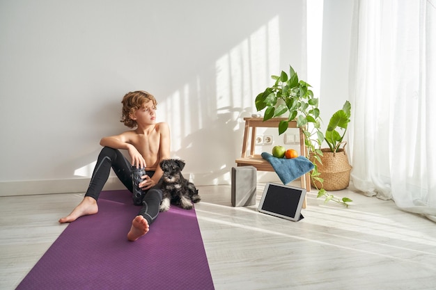 Kid sitting against dog on mat after yoga training