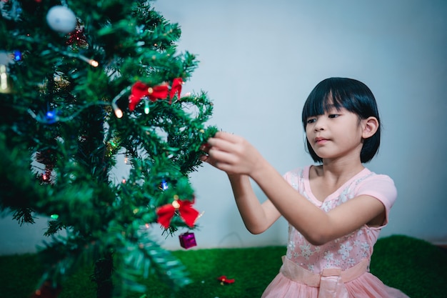 Kid sitting christmas tree for festival season