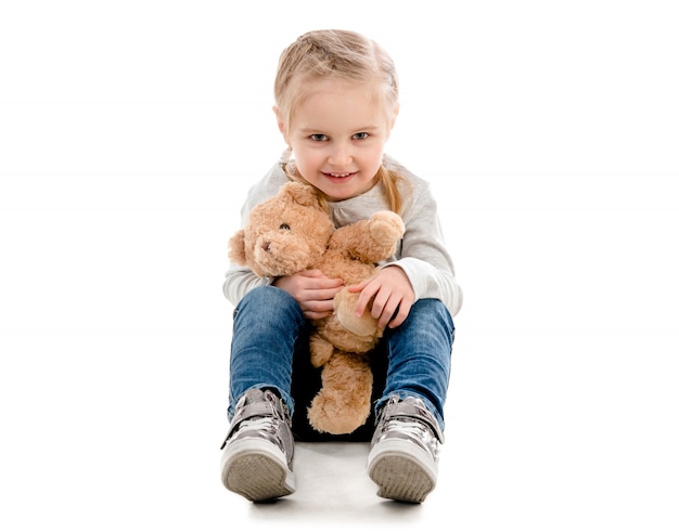 Kid sitting and hugging teddy, isolated