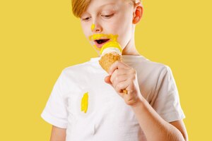 Kid spilling ice cream. clothes ruining. a boy eating banana ice cream on a yellow background