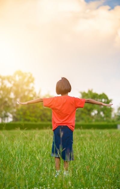 Kid in piedi e allungare le braccia o estendere le braccia nei campi di erba