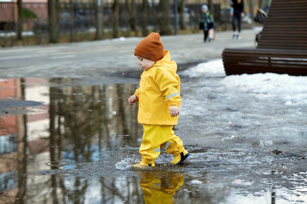 Photo a kid on the street running through puddles