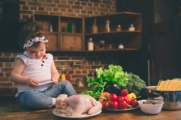 Kid on the table in the kitchen using a smartphone