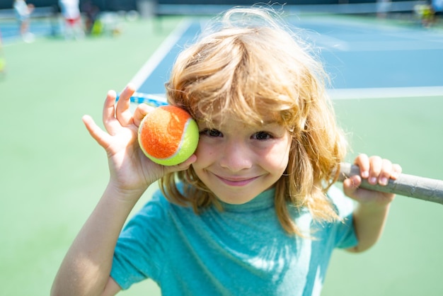 ラケットとボールを持ったテニスコートの子供テニスプレーヤー。