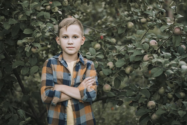 Kid tienerjongen die een appel plukt van een boom in een tuin