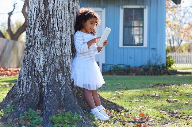 Kid toddler girl with tablet pc playing outdoor