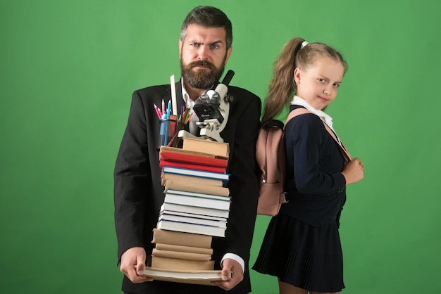 Kid and tutor hold pile of books and stationery