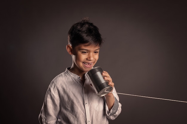 Kid using a can as telephone on a gray