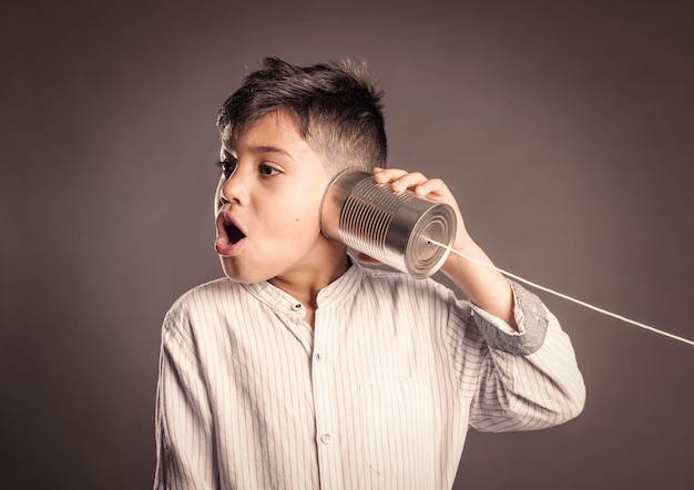 Kid using a can as telephone on a gray