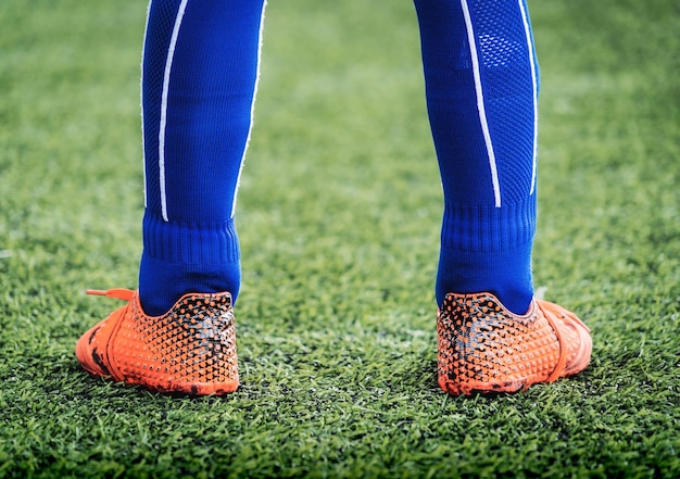 Kid voetballer voeten gesloten op een groen grasveld voor jeugdvoetbal trainingsconcept