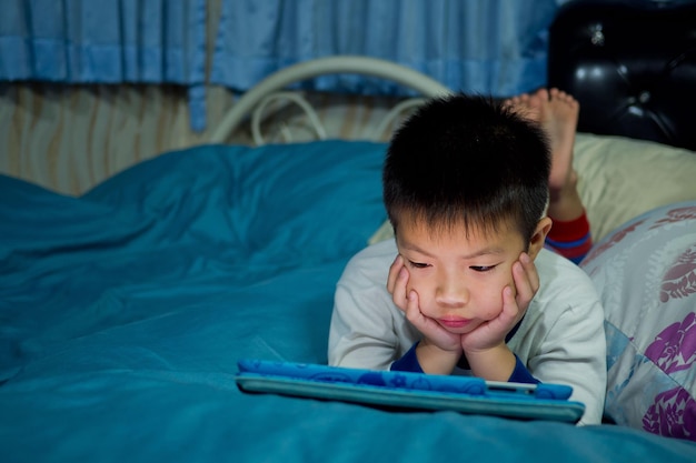 kid watching tablet on the bed, child addicted cartoon