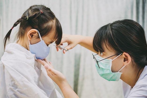 Bambino che indossa una maschera per il viso per prevenire il coronavirus mentre taglia i capelli nel barbiere