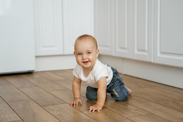 a kid in a white Tshirt crawls on the kitchen floor