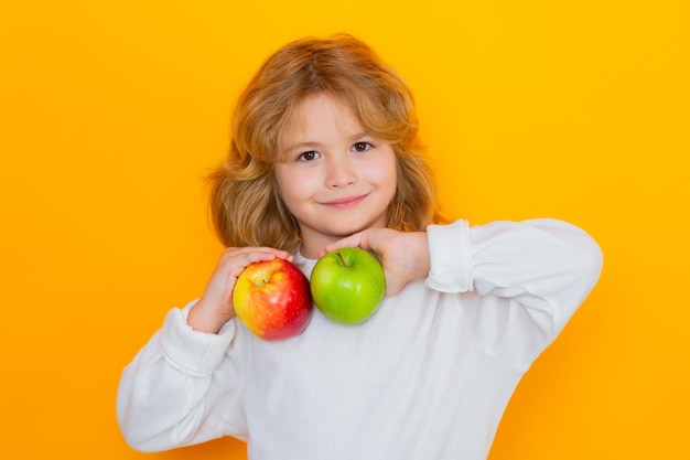 Фото Ребенок с яблоком в студии студийный портрет милого ребенка, держащего яблоко на желтом фоне