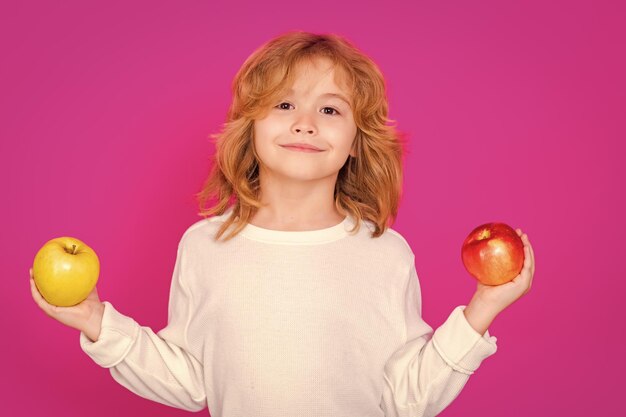 Ребёнок с яблоком в студии Студийный портрет милого ребенка держит яблоко, изолированное на розовом фоне