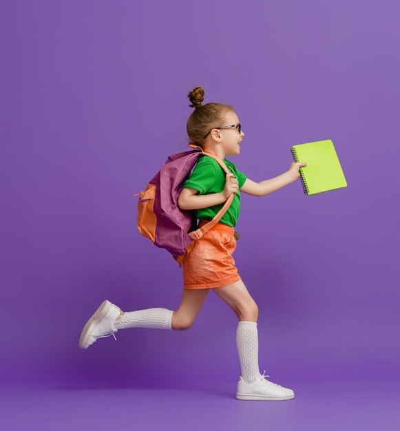 Kid with backpack on color background