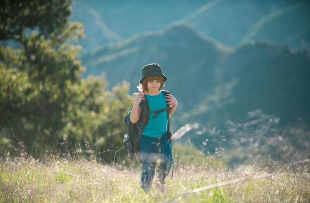 Kid with backpack hiking in mountains boy local tourist goes on a local hike