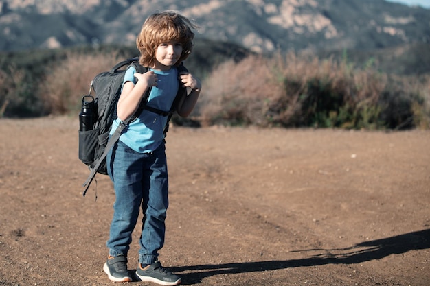 Photo kid with backpack hiking in scenic mountains boy child local tourist goes on a local hike