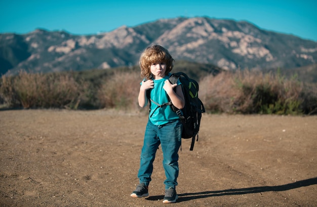 Photo kid with backpack hiking in scenic mountains boy local tourist goes on a local hike