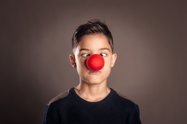 Kid with a clown nose on a gray