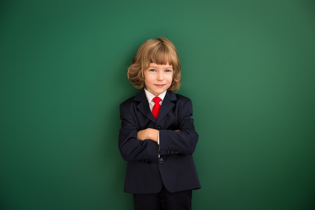 Kid with drawn robot hands against blackboard. Schoolchild in class