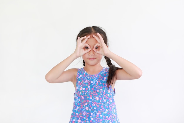 Kid with hands glasses in front of her eyes isolated on white wall