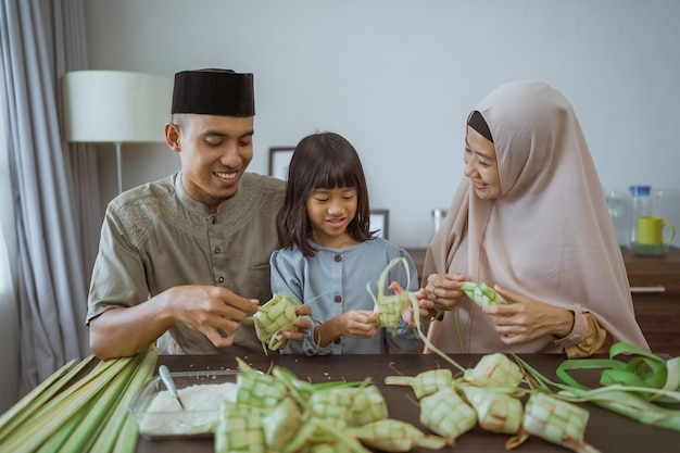 Kid with her parent making a ketupat at home