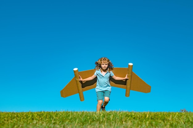 Фото Ребенок с реактивным ранцем супергерой ребенок-пилот на фоне летнего неба мальчик с бумажным самолетом летит в