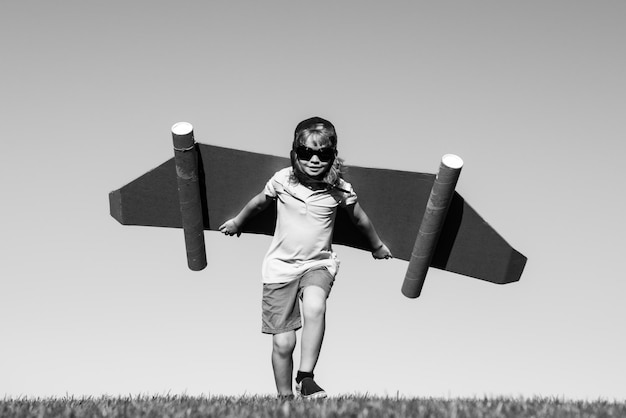 Kid with jet pack superhero child pilot against summer sky background boy with paper plane flight to