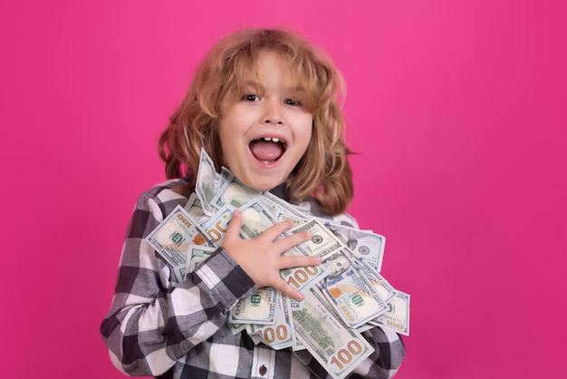 Kid with lots of money dollar banknotes isolated over pink red studio background