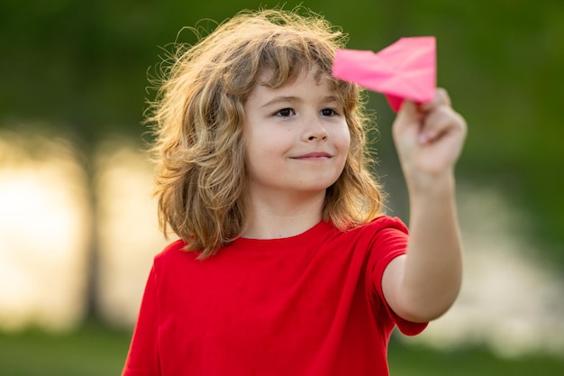 Kid with plane child throwing paper plane cute blonde child play with paper plane outdoor child play
