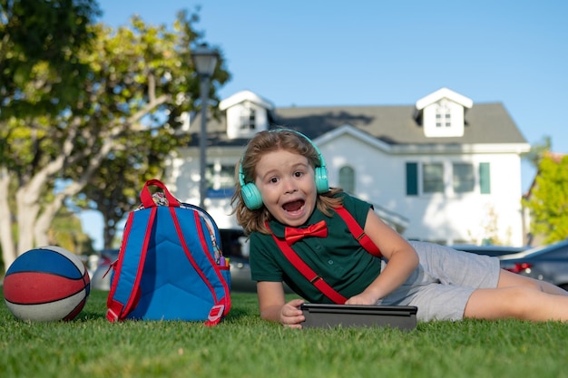 短いとシャツの小さな子供屋外学校を身に着けている庭で屋外に座っているタブレットデバイスを持つ子供
