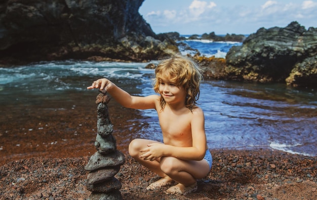 Kid with zen stones on sea beach meditation spa and harmony Calm balance concept