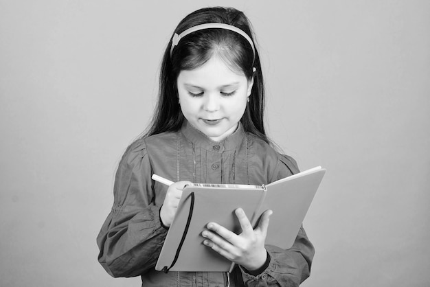 子供向けの本を書く本のコンセプト開発と教育宿題の練習作文を書く文学クラブ個人的な日記勉強して学ぶ詩の作者女の子は本を青い背景に持つ
