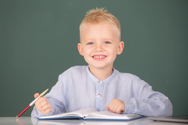 Kid writing in notebook in class little schoolboy study in a classroom at elementary school