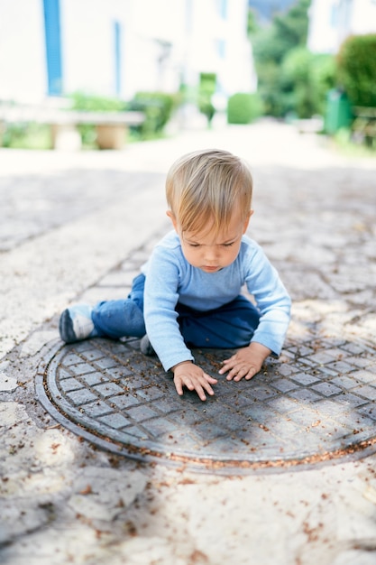 Kid zit op een metalen luik in de tuin