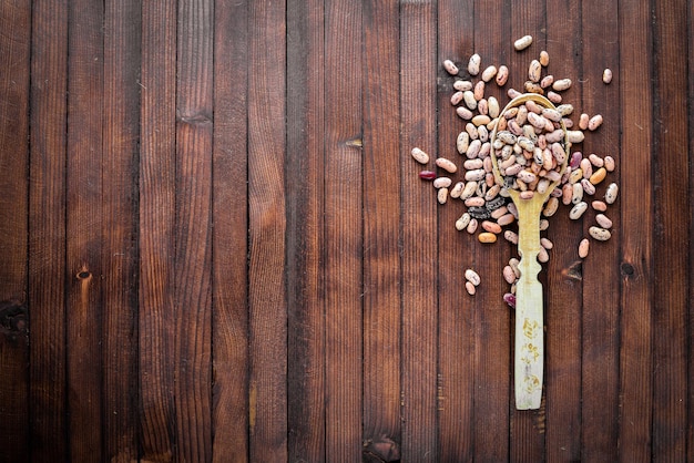 Kidney beans. Wooden spoon. On Wooden background. Top view.