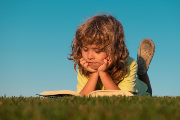 子供たちは自由と屈託のない子供たちを冒険します。草の学校の夢の日に外で本を読んでいるかわいい子供たち