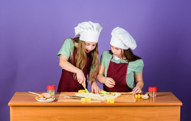 Kids aprons and chef hats cooking Family recipe Culinary education Mothers day Baking ginger cookies Girls sisters having fun ginger dough Homemade cookies best Kids baking cookies together