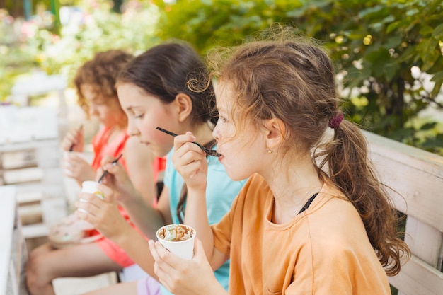 子供たちは屋外カフェでアイスクリームを食べています