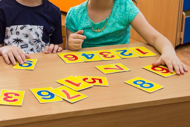 Foto i bambini giocano a giochi educativi un bambino all'asilo le mani di un bambino carte di matematica