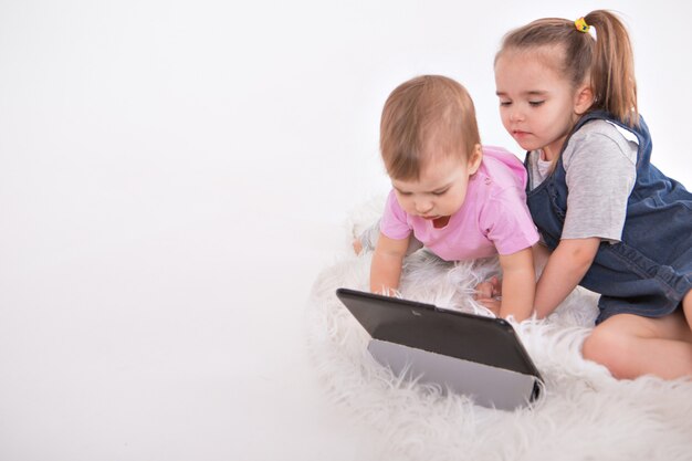 The kids are watching cartoons on the tablet. Home schooling for girls during quarantine