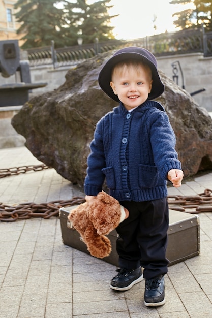 Bambini bambino in abiti primaverili autunnali retrò. piccolo bambino seduto sorridente nella natura, sciarpa intorno al collo, clima fresco. emozioni luminose sul suo volto. russia, sverdlovsk, 29 settembre 2018