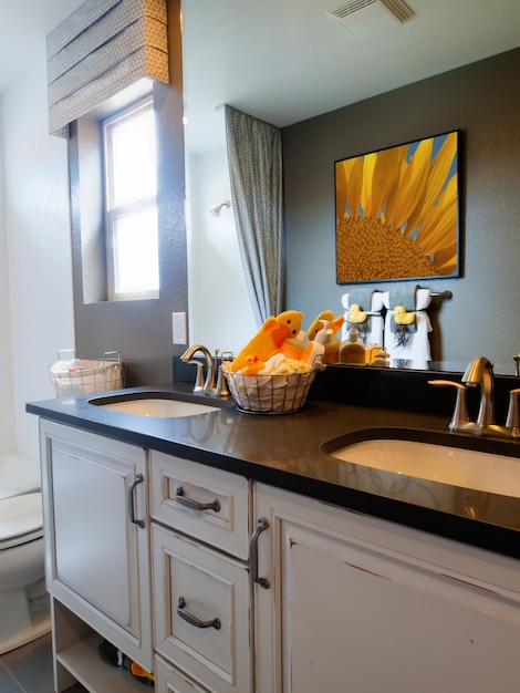 Kids bathroom with yellow ducks decor and white cabinets.