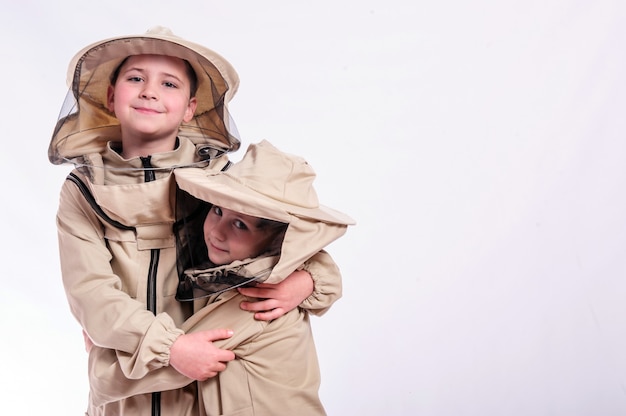 Photo kids in beekeeper's suits posing in studio white background.