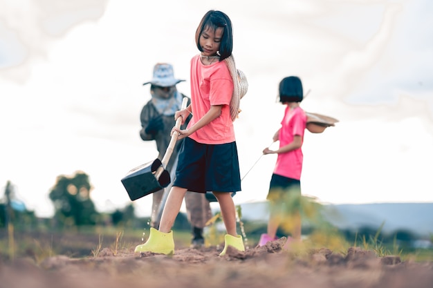 Kids and blurred grandmother working and watering the vegetable in organic farm in rural