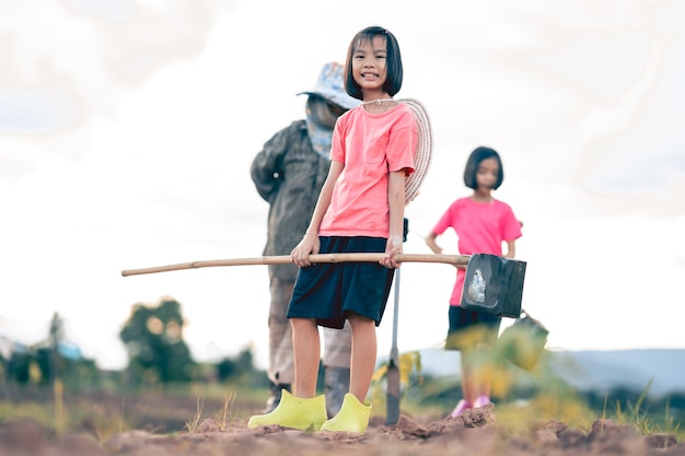 Kids and blurred grandmother working and watering the vegetable in organic farm in rural