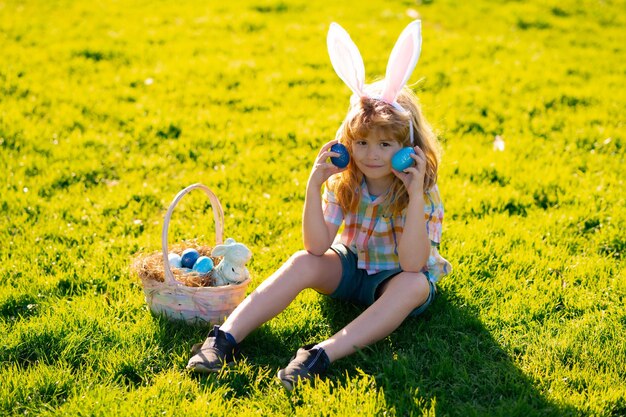 Kids boy in bunny ears hunting easter eggs outdoor child having easter in park easter egg hunt